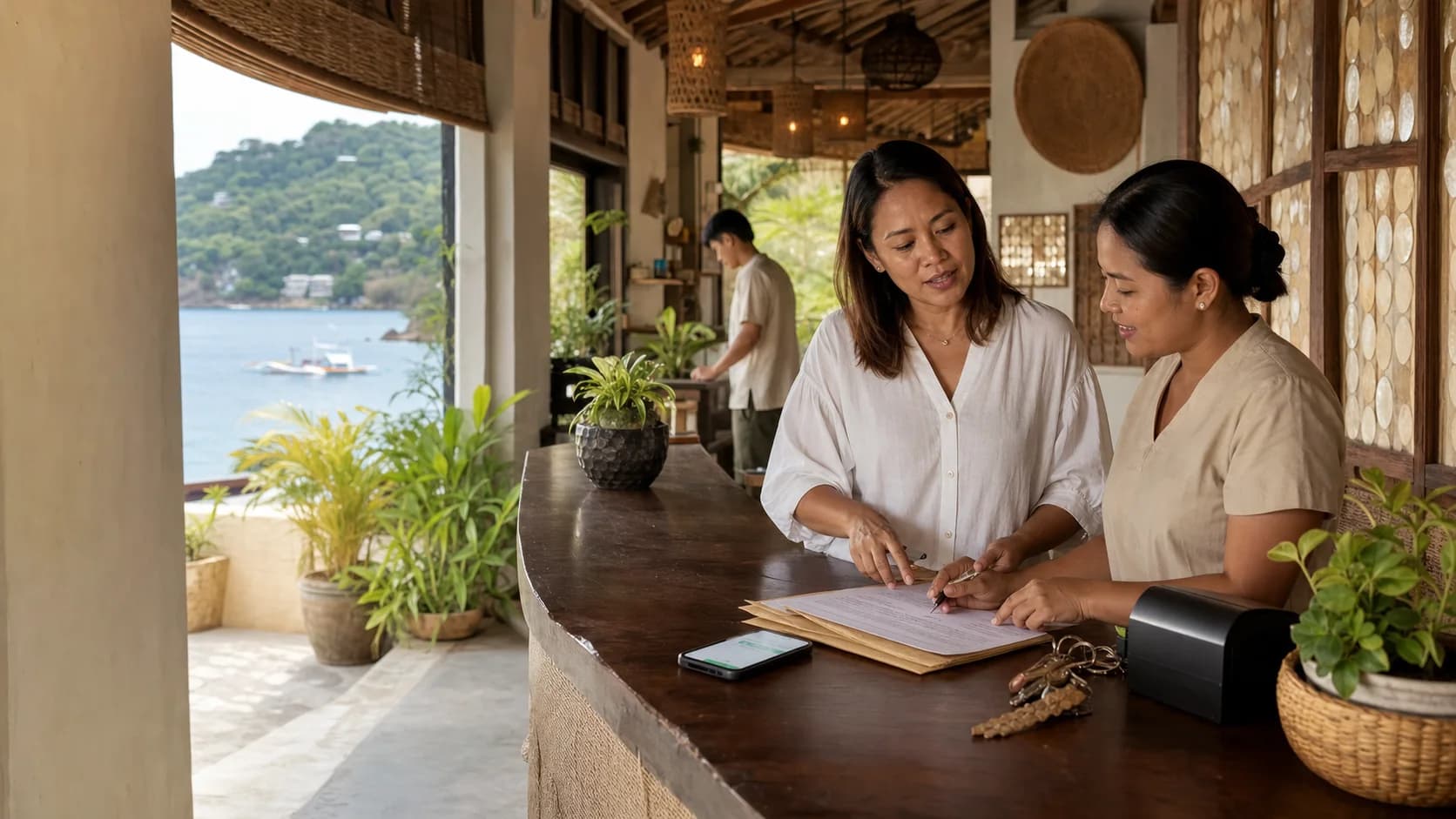 A guest checking in at an open-air Philippine hotel reception, with staff handing over the room key beside a sea view.